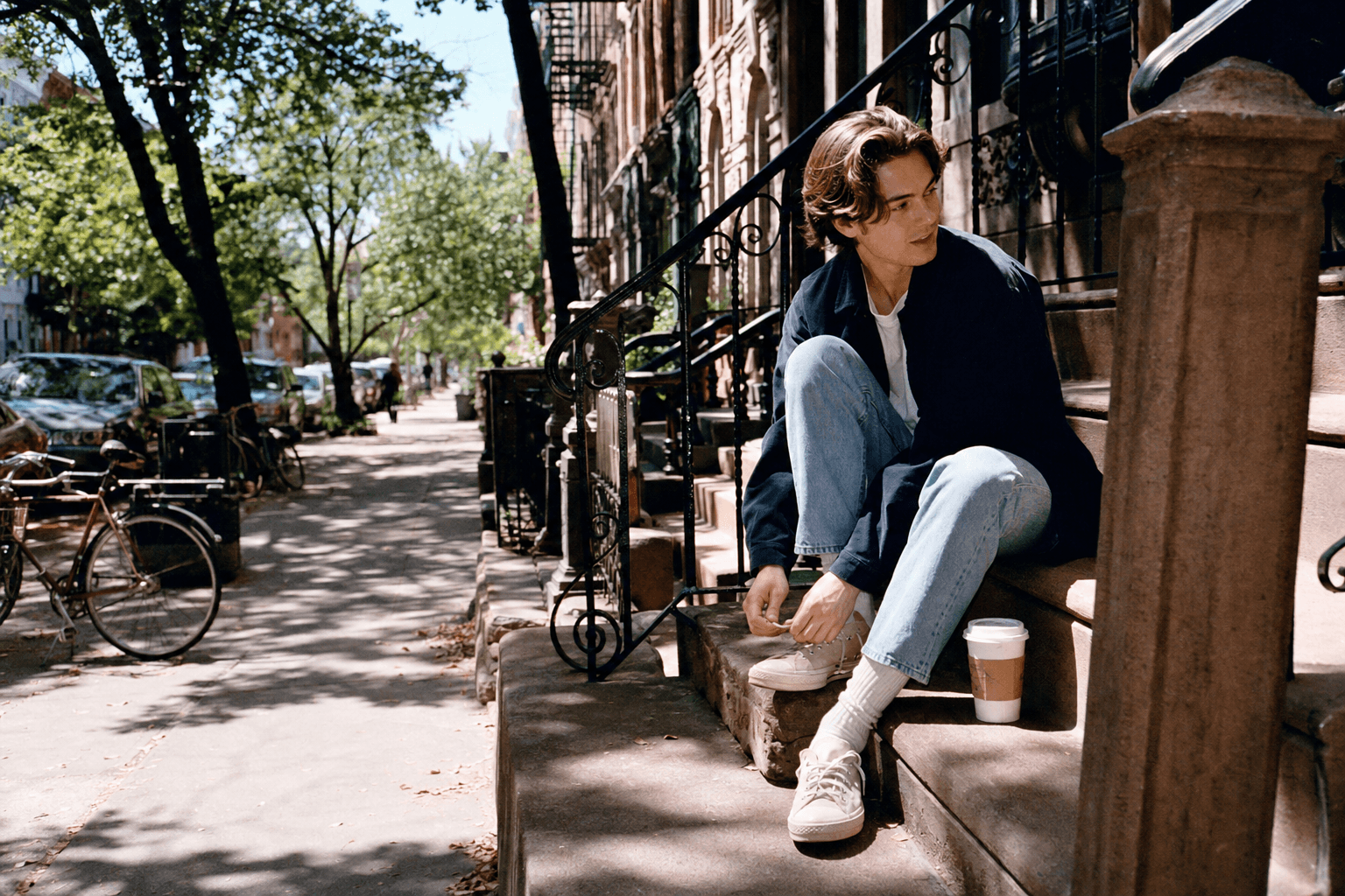 A person sitting on a brownstone stoop in morning light