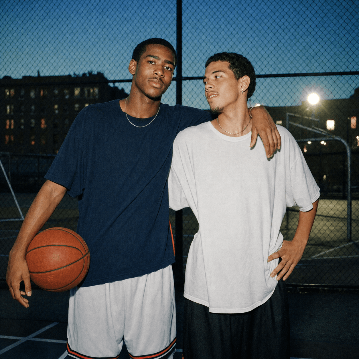 Two friends posing together on a basketball court